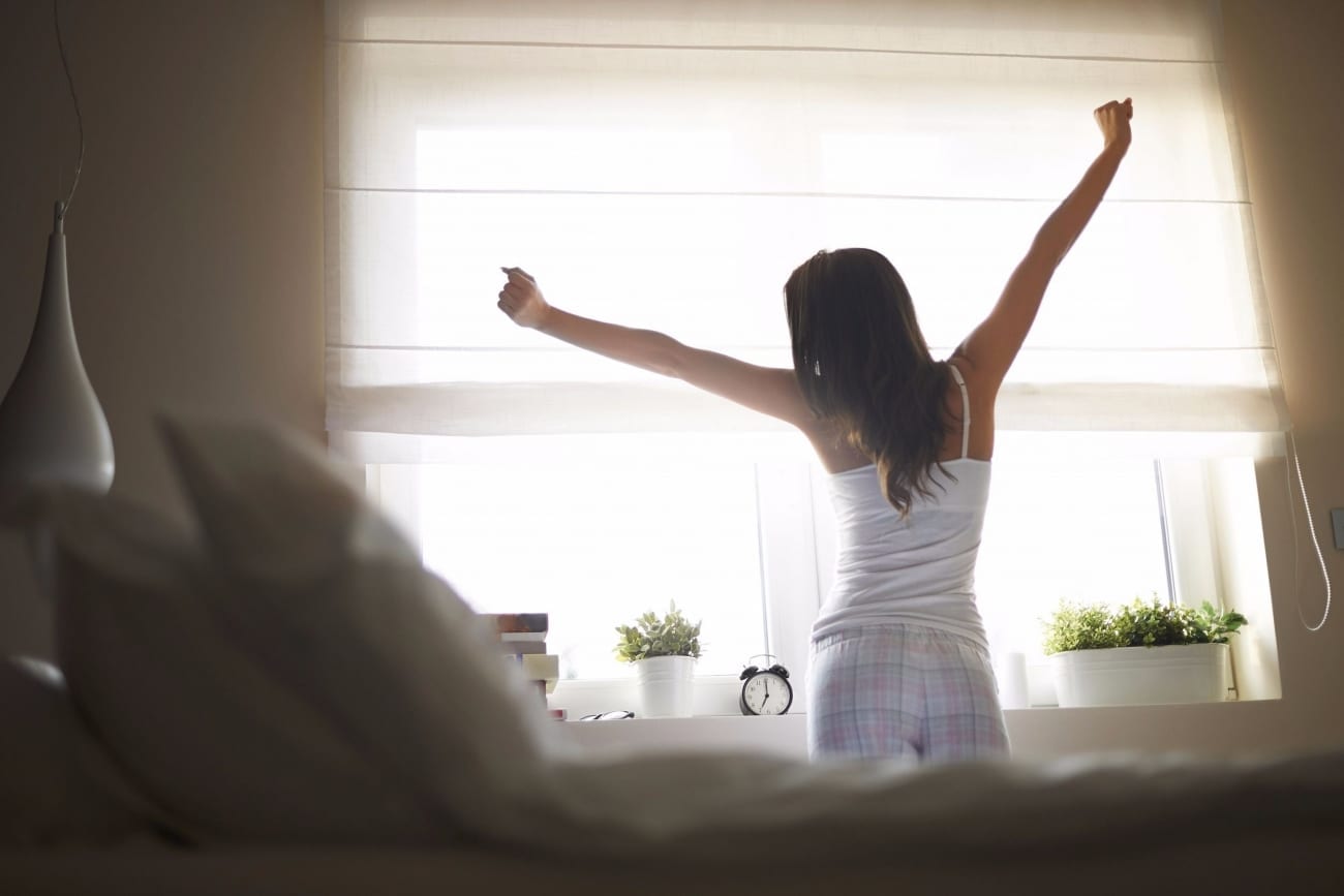 Young woman waking up in bed Yoga Health Coaching